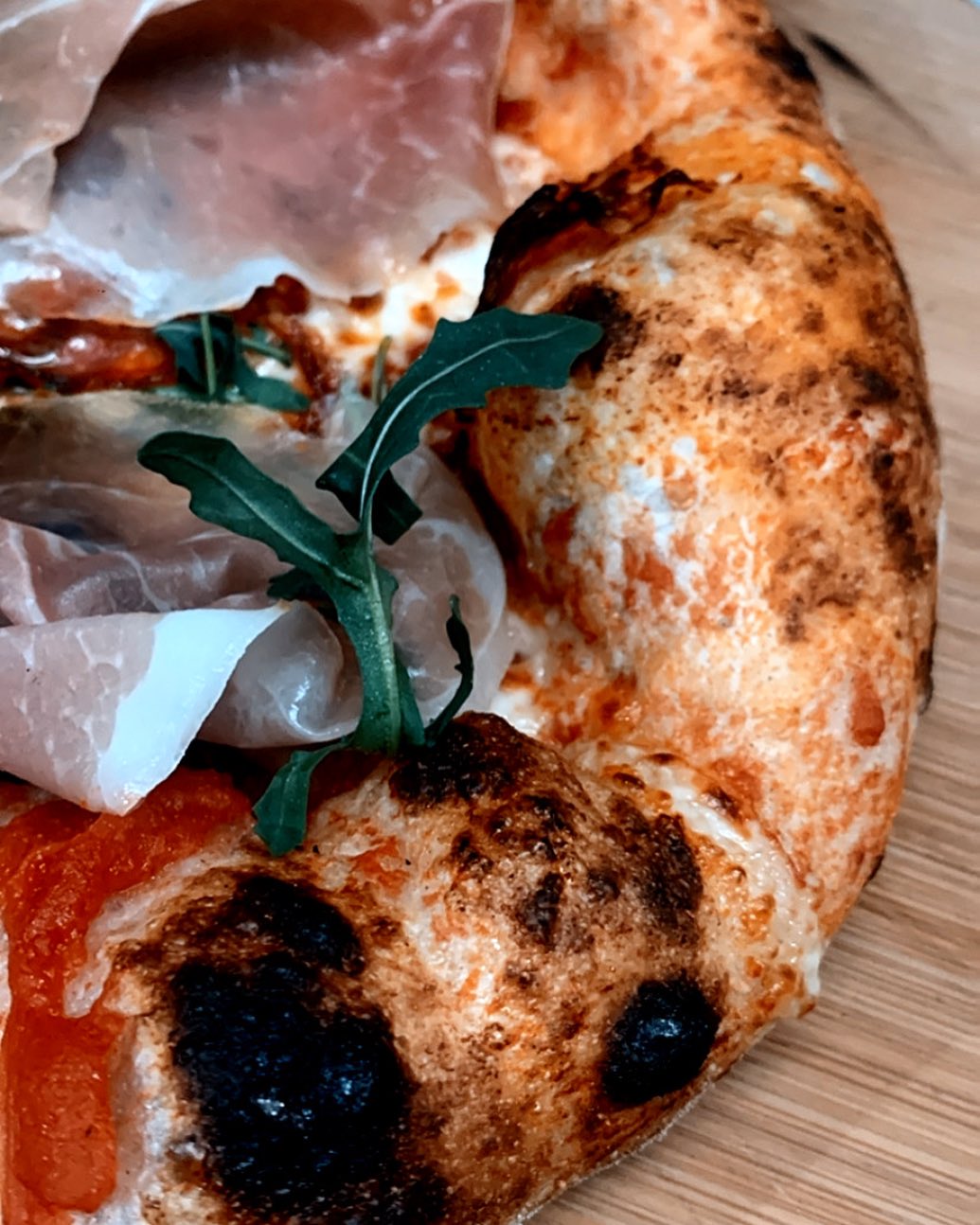 Pizza topped with prosciutto and arugula.