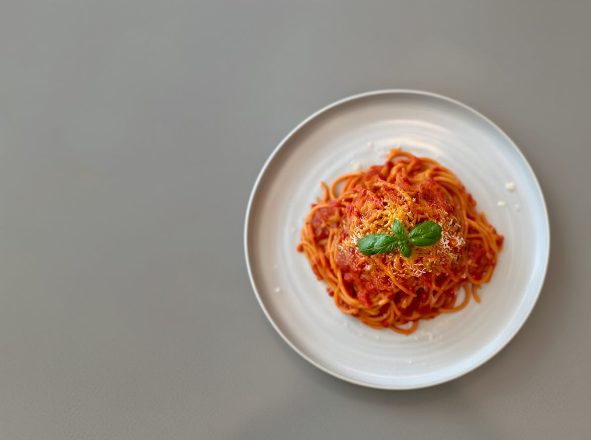 Minimal plated spaghetti on a neutral tabletop.